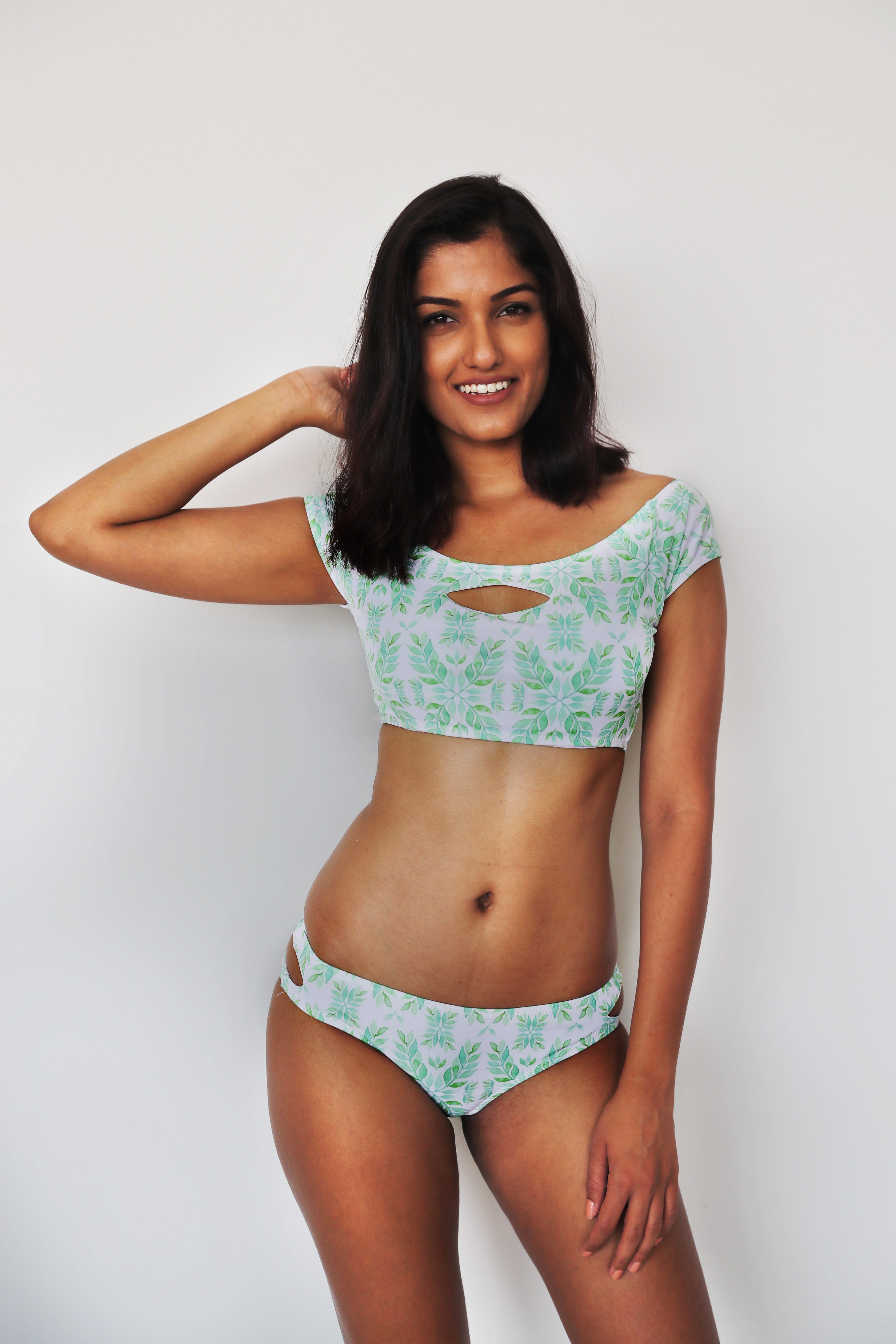 woman wearing a two piece bikini set with a green leaf print on a white background.