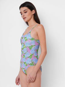 woman is wearing a one piece swimsuit with a blue hydrangea print on a pink background