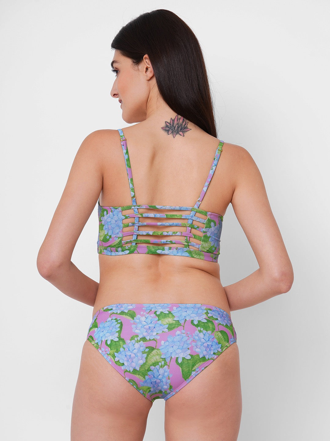 woman is wearing a two piece bikini set with a blue hydrangea print on a pink background