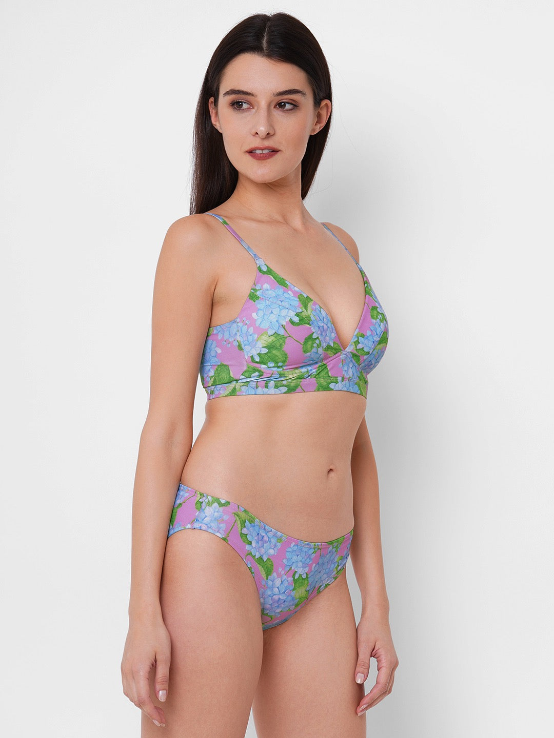 woman is wearing a two piece bikini set with a blue hydrangea print on a pink background