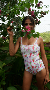 woman is wearing a one piece swimsuit with a sweet pea flower print